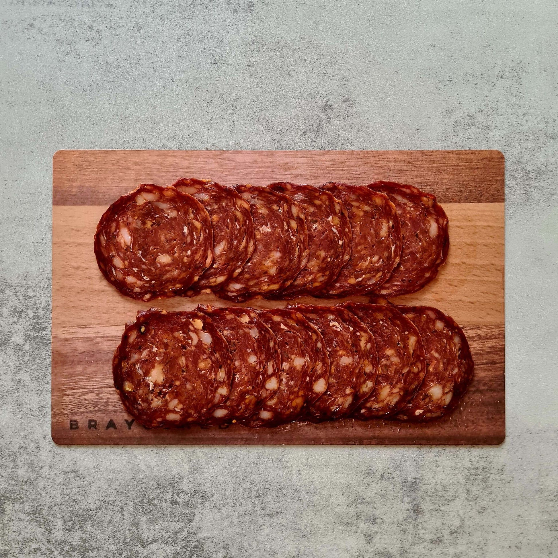 Sliced Hogget Chorizo from Bray Cured arranged on a charcuterie board with accompaniments, showcasing its rich, spicy flavor.