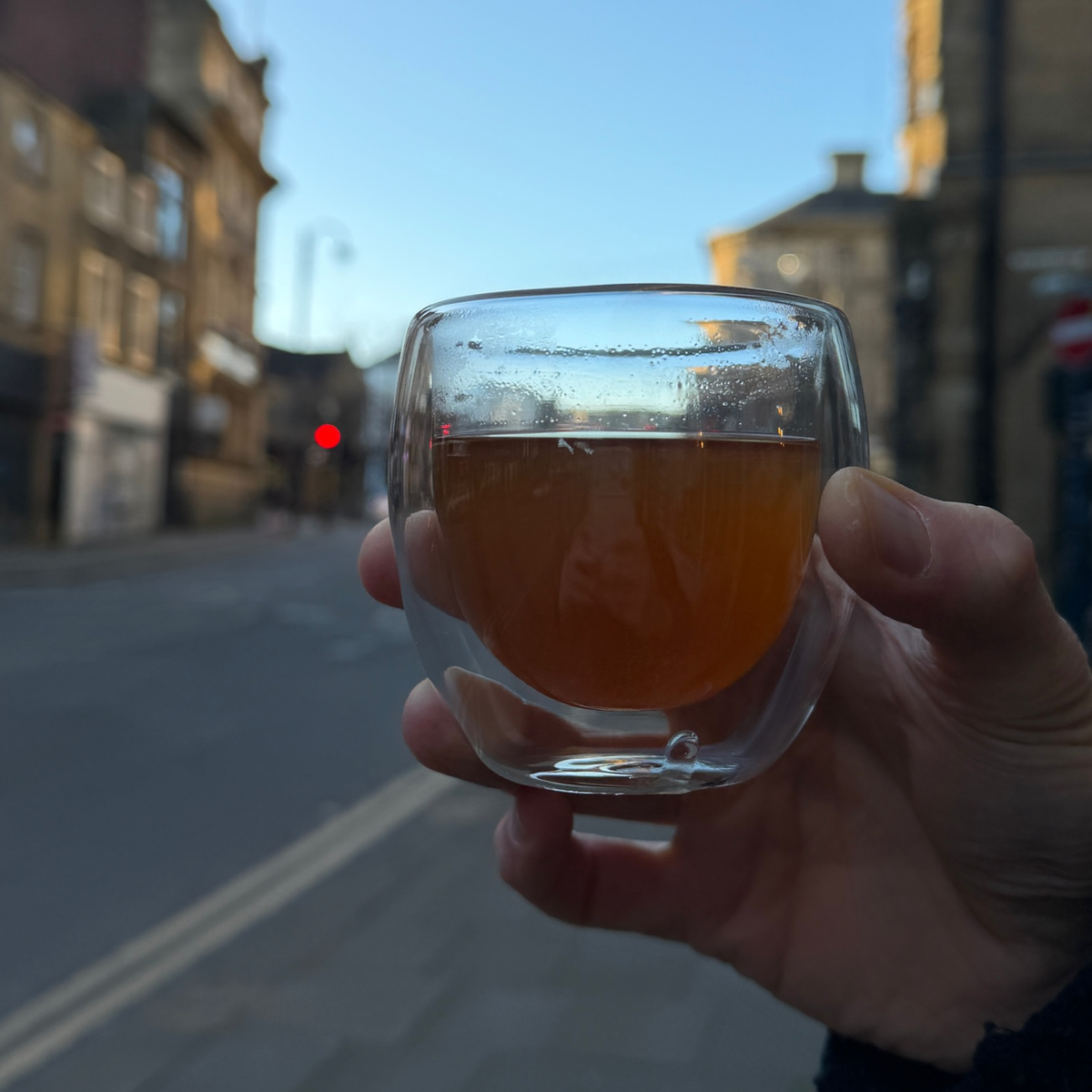 Brewed Porter Hill Tea Company Hojicha green tea in a clear glass cup, showing its rich amber color and steaming hot liquid.