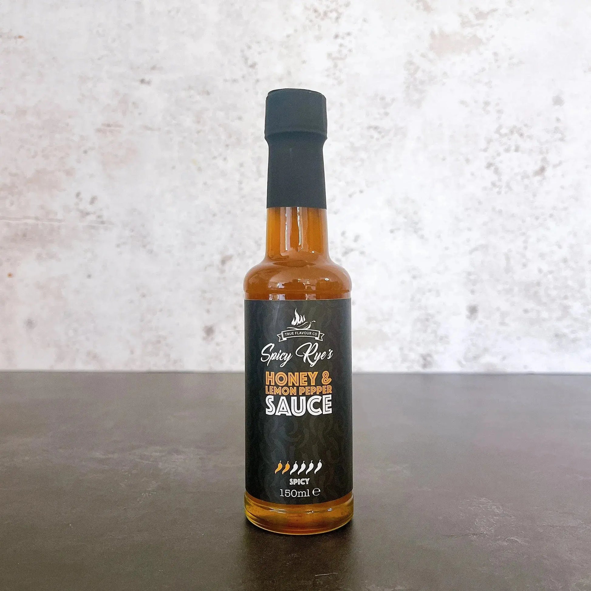 Spicy Ryes honey and lemon pepper hot sauce in a glass bottle with a label, showcasing the flavorful sauce inside.