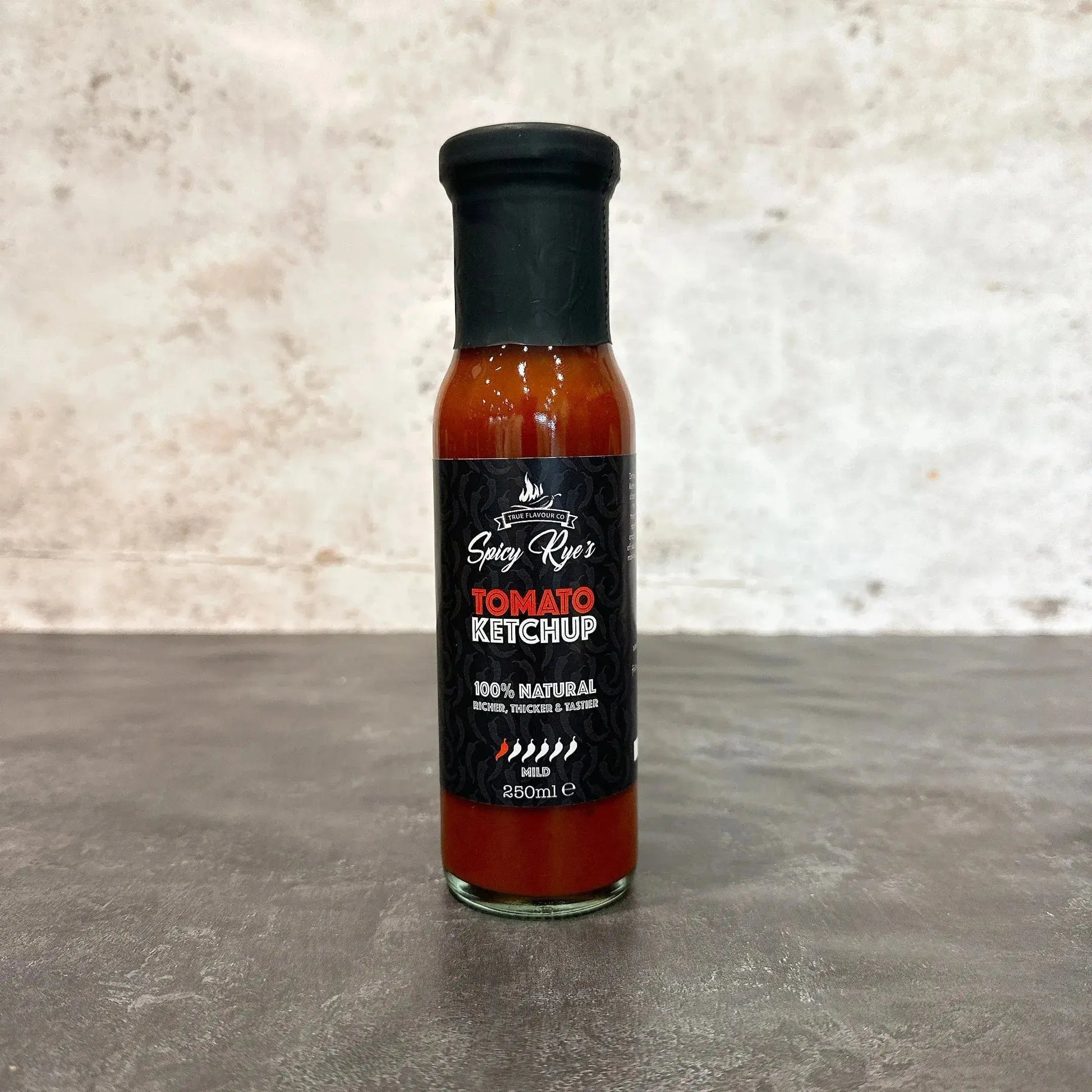 Spicy Ryes hot sauce bottle with tomato ketchup flavor, featuring a red and orange label and a squeeze cap on a white background.