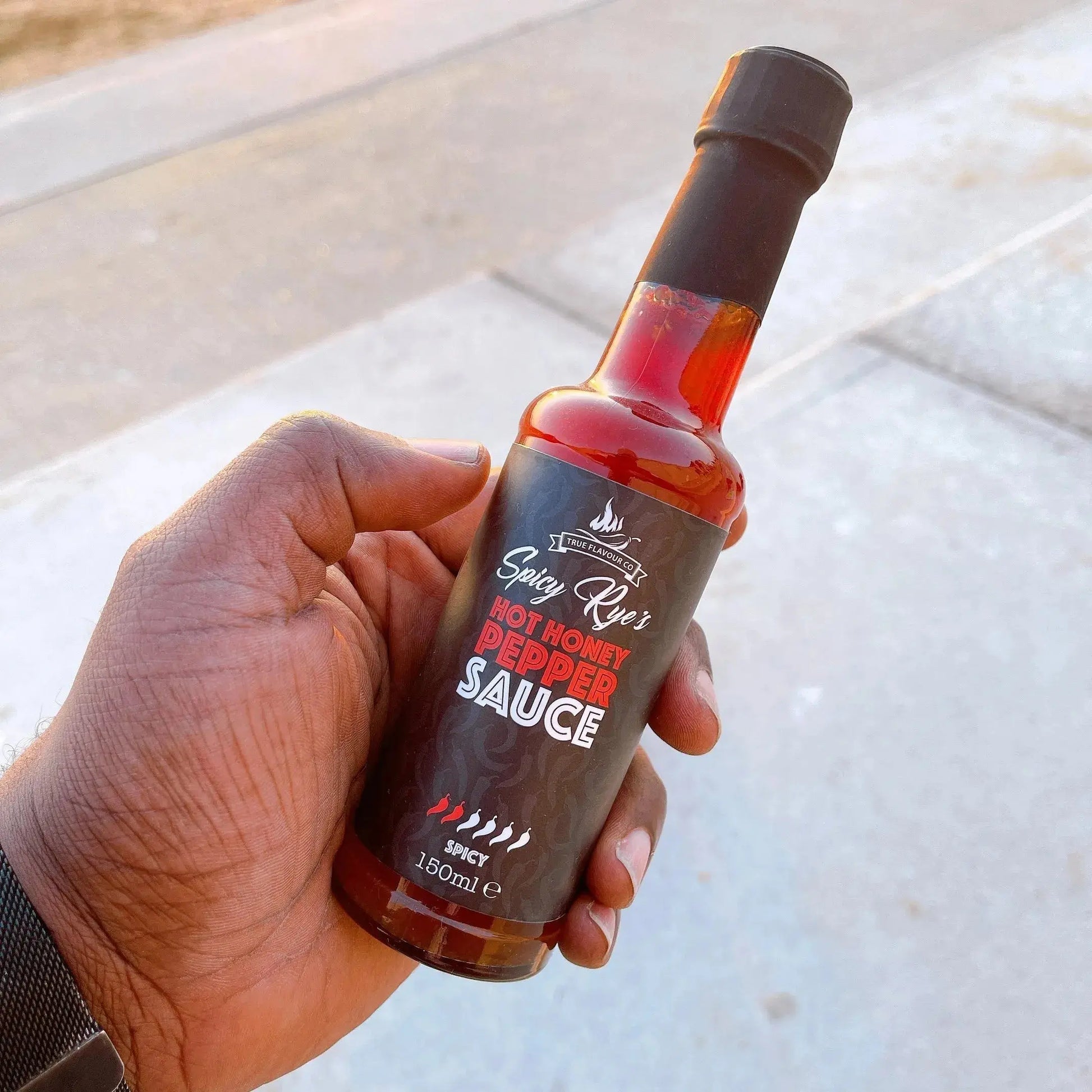 Spicy Ryes Hot Honey Pepper Sauce bottle with red and yellow label, showing the hot sauce inside, on a neutral background.