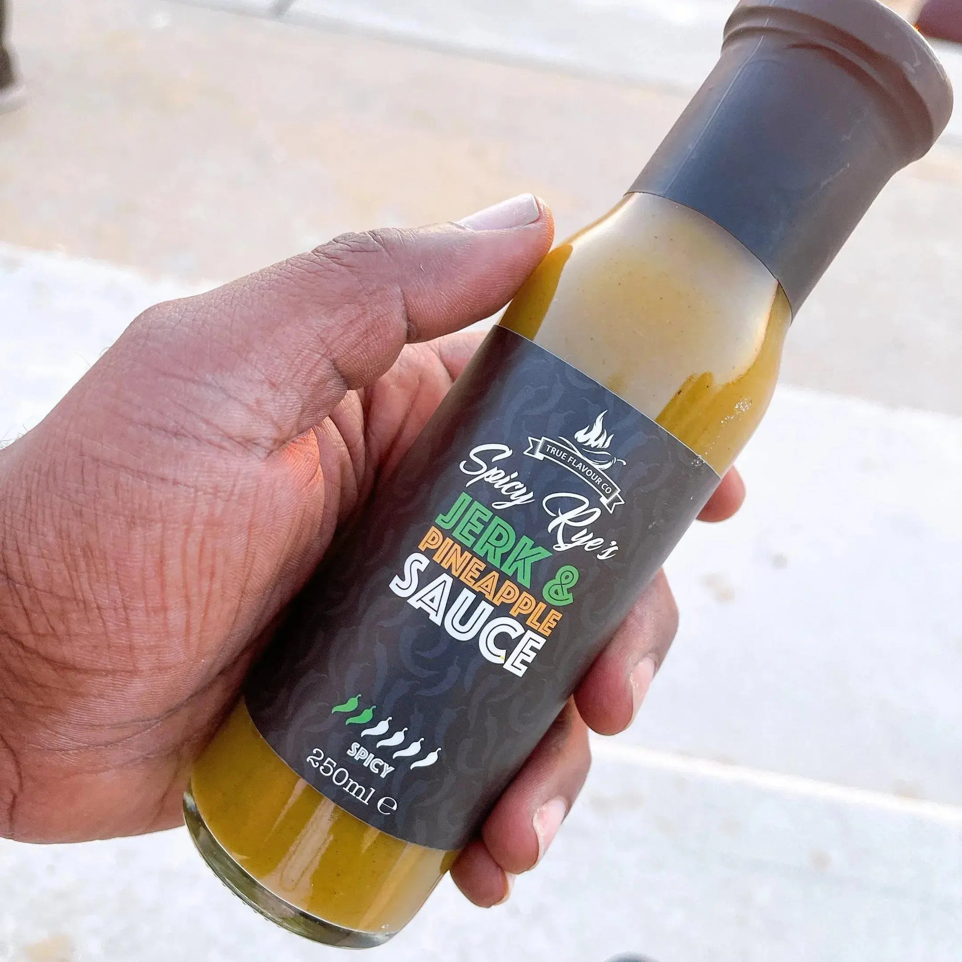 Spicy Ryes jerk and pineapple hot sauce bottle with vibrant label, showcasing the flavorful sauce inside.