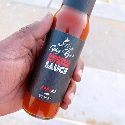 Spicy Ryes Original Hot Pepper Sauce bottle with bright red hot sauce visible in a glass bottle on a wooden surface.