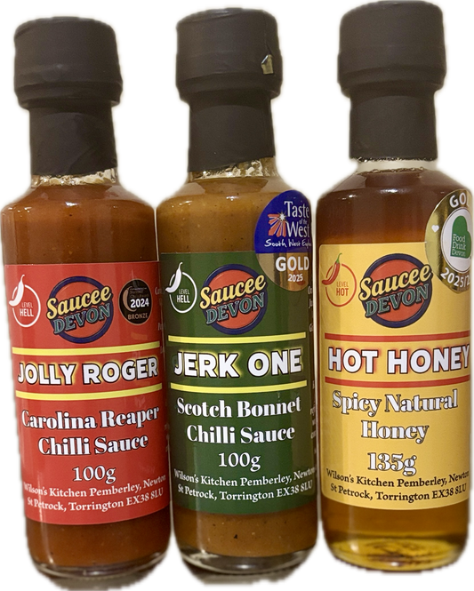 Assorted artisan chili sauces from Wilson’s Kitchen, featuring three vibrant hot sauce bottles with colorful labels.