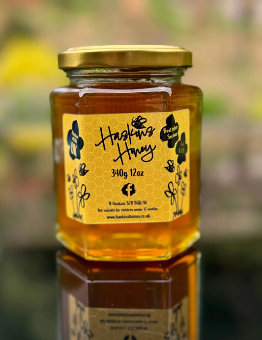 Jar of Haskins Honey Premium Garden Reserve honey with a golden, viscous appearance and a floral label design.