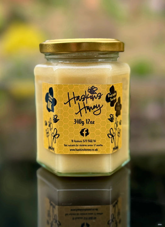Jar of Meadow Cream honey by Haskins Honey with a golden, smooth honey surface in a clear glass jar.