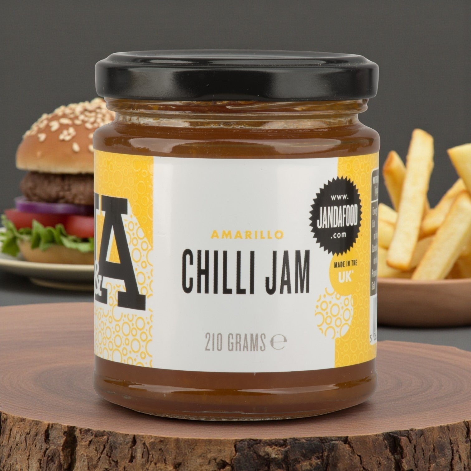 Janda Amarillo Yellow Chilli Jam 210g jar showing vibrant yellow chili spread with a spoon, perfect for cheese and barbecue dishes.