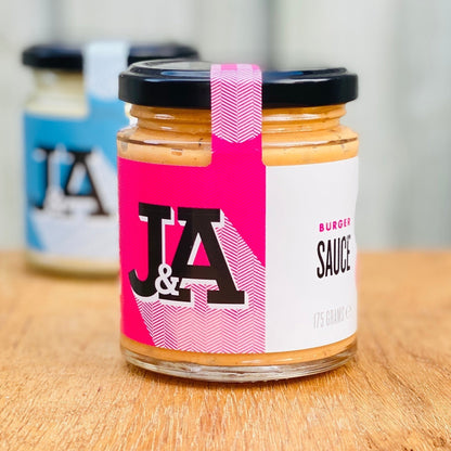 Janda Food vegan burger sauce in a glass jar with a pink and white label on a wooden surface