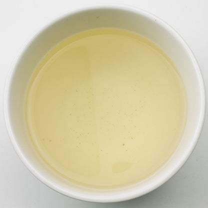 Bright image of Jasmine Dragon Pearl Green Tea liquor by PekoeTea Edinburgh, showcasing glossy pearl-shaped tea leaves.