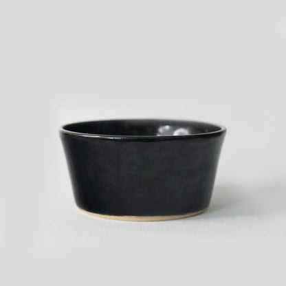 Jet black ceramic breakfast bowl by Katie L Thompson Designs, showcasing a sleek, glossy finish and smooth round shape.