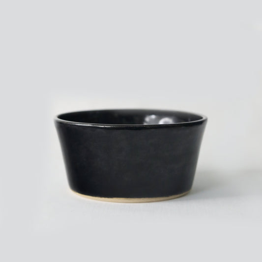 Jet black ceramic breakfast bowl by Katie L Thompson Designs, showcasing a sleek, glossy finish and smooth round shape.