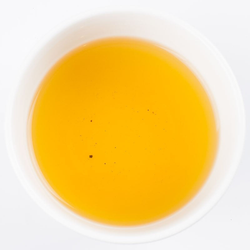 Golden brewed Kinnettles Scottish Grown Tea from PekoeTea Edinburgh in a clear cup, showcasing vibrant tea liquor.