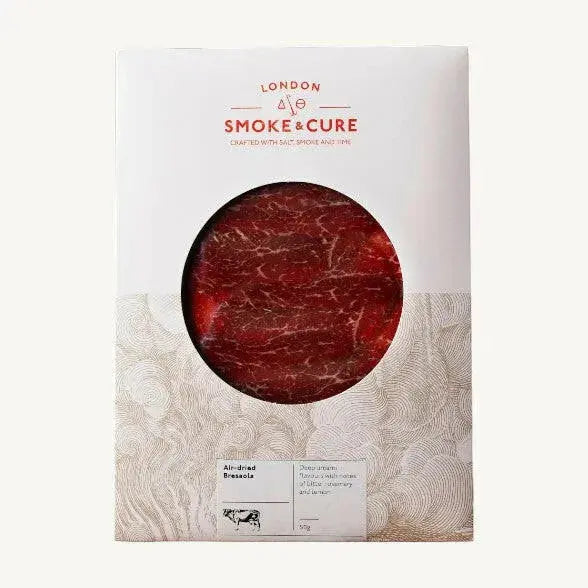Thin slices of London Smoke & Cure Bresaola from ArtisanBox Selection, arranged on a wooden board for charcuterie presentation.