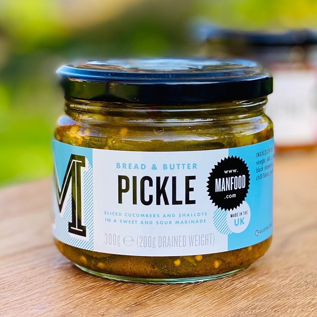 Jar of Manfood bread and butter pickles with sliced pickles visible in clear glass jar on a white background.