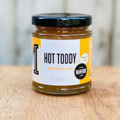 Manfood Hot Toddy Marmalade preserve in a clear jar, showcasing its vibrant orange color and label with branding and flavor details.