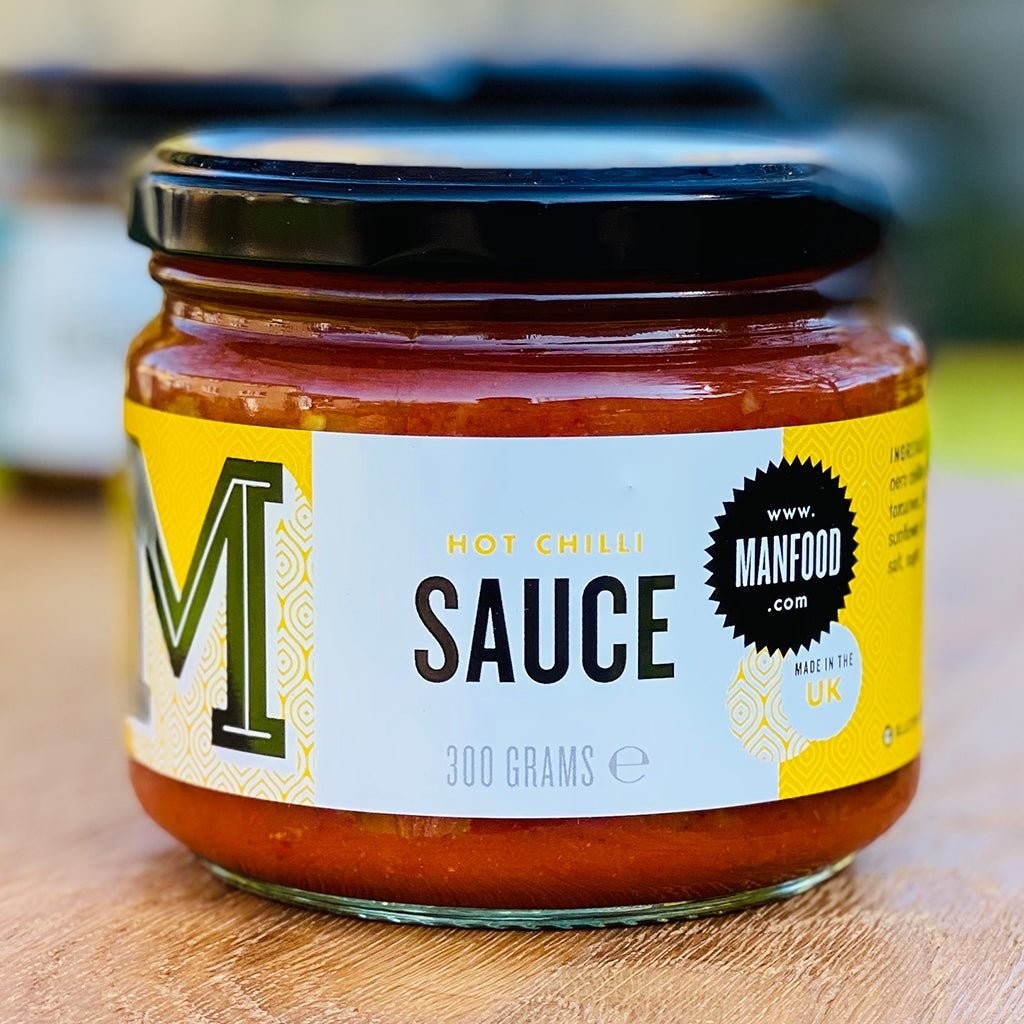 Manfood hot chilli sauce in a 300g glass jar with a yellow and white label featuring barrel-aged chillies.