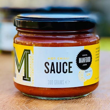 Manfood hot chilli sauce in a 300g glass jar with a yellow and white label featuring barrel-aged chillies.