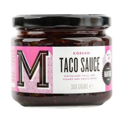 Manfood Korean Taco Sauce in a glass jar with a pink and white label featuring gochujang, soy, and sesame.
