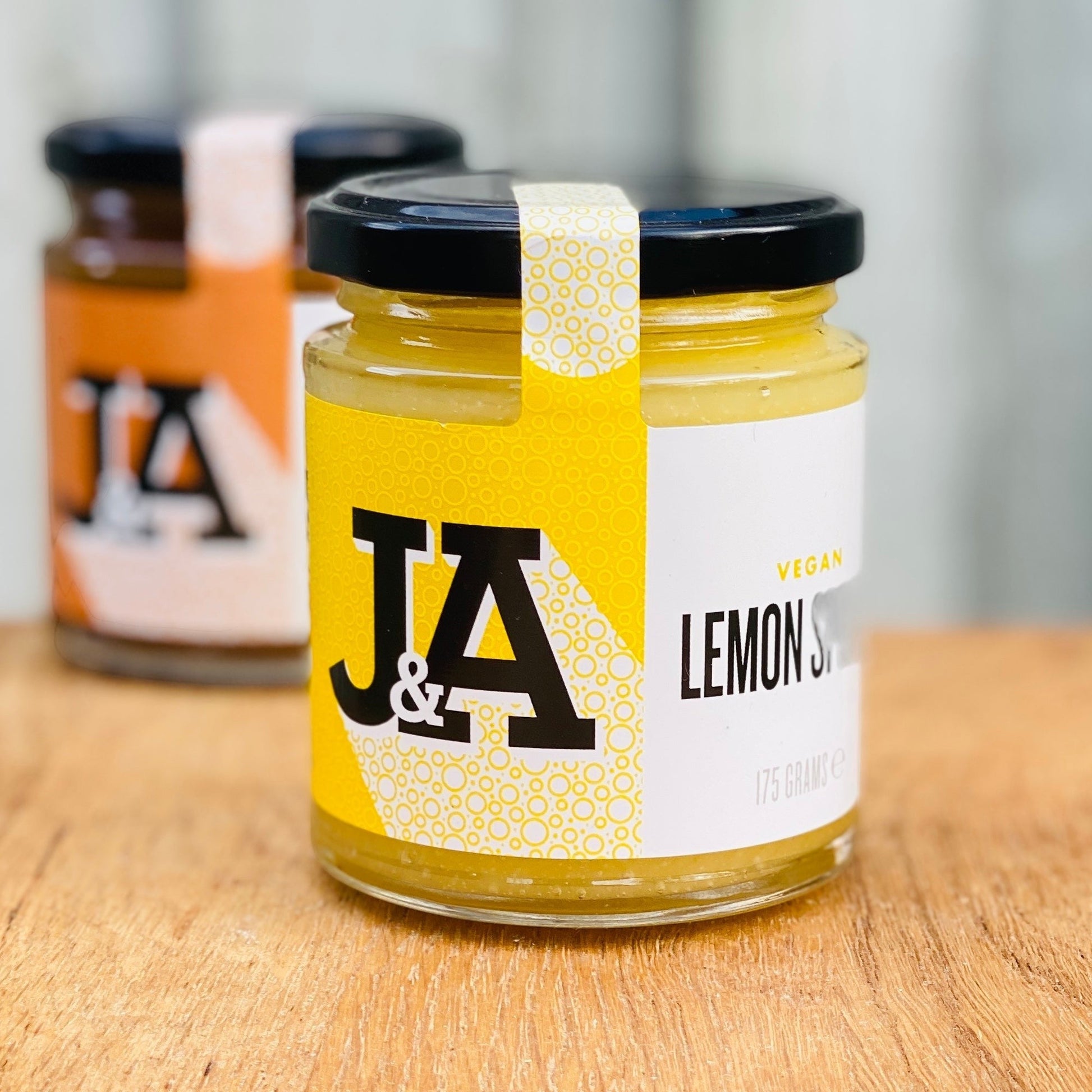 Jar of Manfood vegan lemon curd with a bright yellow lemon spread inside and a label displaying the product name.