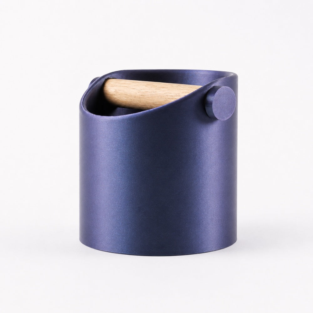 Minimalist coffee knock box with a sleek design and real oak wood bar, featuring a galaxy nebulae background.