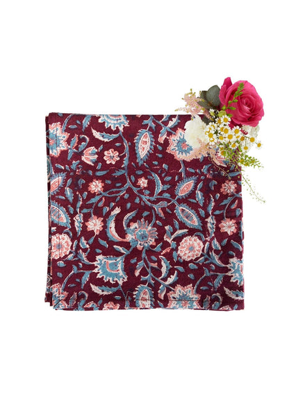 Set of four maroon cloth table napkins by Casa by Josephine Jenno, neatly folded and arranged on a dining table.