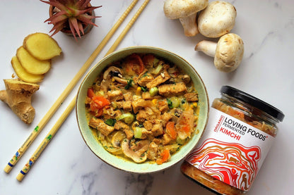Bowl of Loving Foods organic kimchi with vibrant fermented vegetables and noodles, served in a white ceramic bowl.