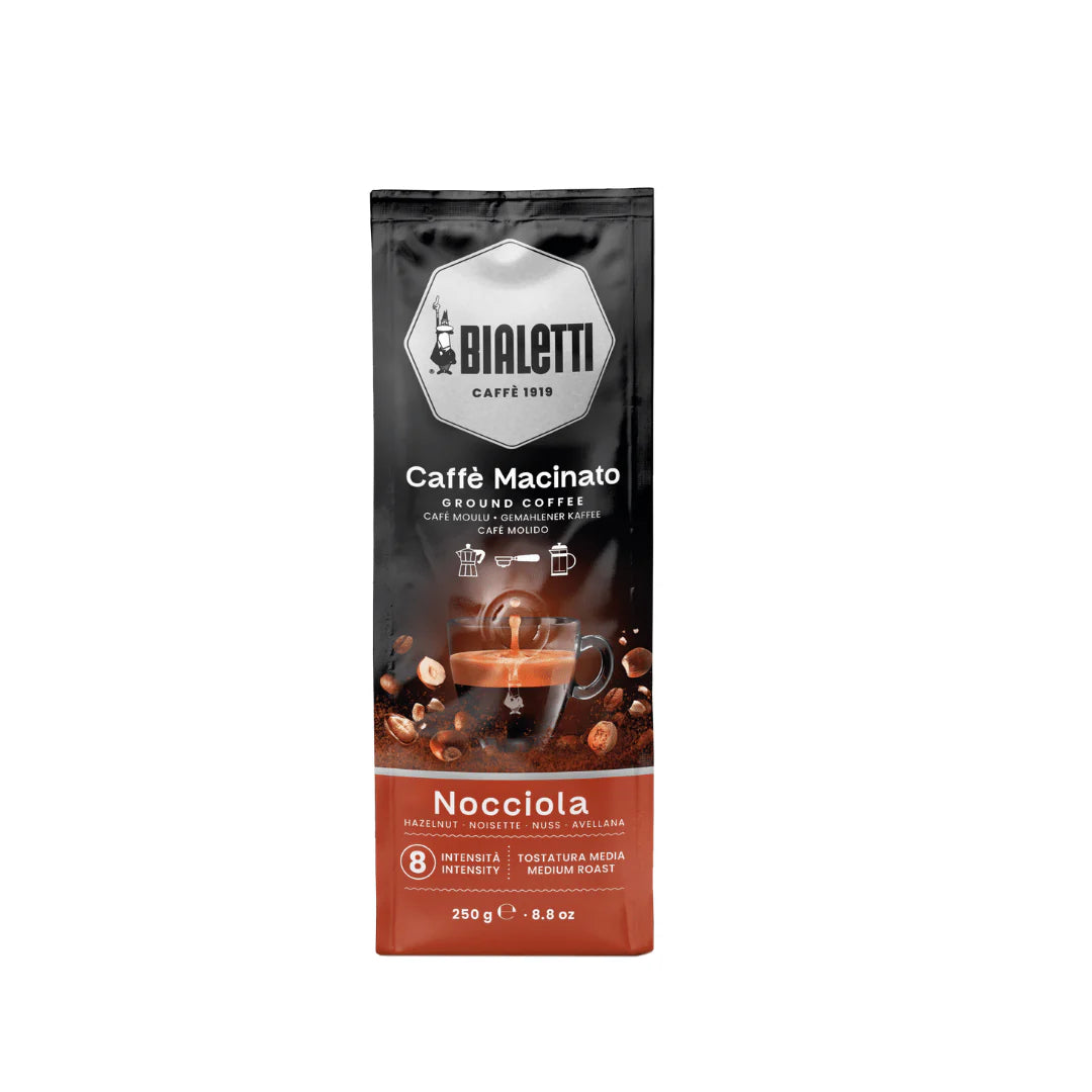 Bialetti Brew Italia Omni Ground Coffee in hazelnut flavor, with a bag of aromatic ground coffee on a wooden surface.