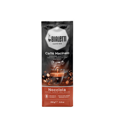 Bialetti Brew Italia Omni Ground Coffee in hazelnut flavor, with a bag of aromatic ground coffee on a wooden surface.