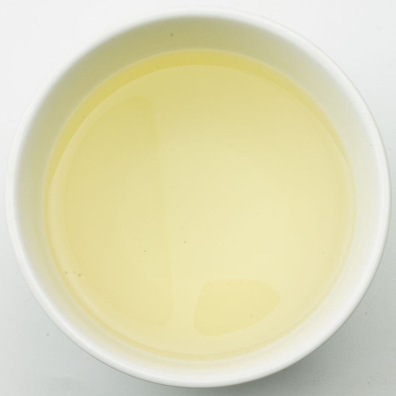 PekoeTea Edinburgh Pai Mu Dan white tea liquor in a clear glass cup showing light golden color