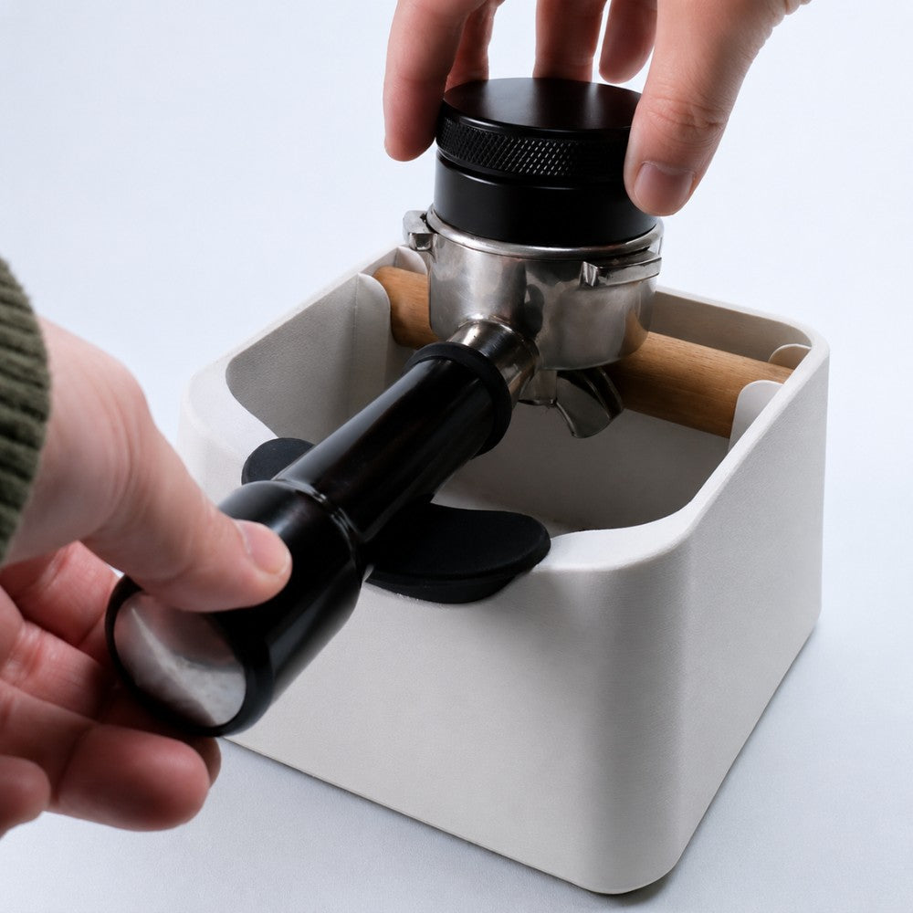 KNOCDIC® The Pod Coffee Knock Box with tamping tool for espresso preparation, shown with coffee grounds and tamper in a professional setting.