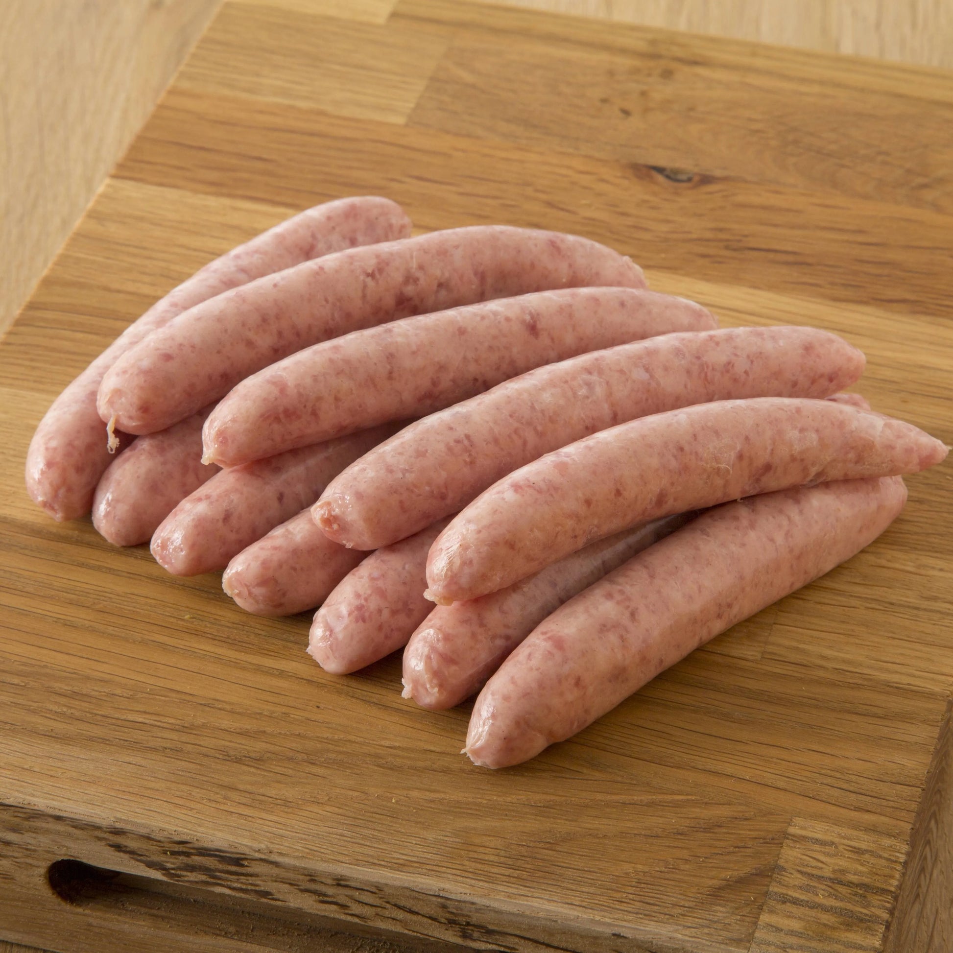 Primrose Herd cranberry and rosemary pork chipolata sausages, cooked and arranged on a plate.