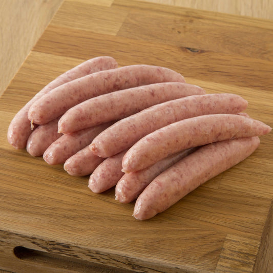 Primrose Herd cranberry and rosemary pork chipolatas sausages, cooked and served on a plate with herbs and fresh cranberries.