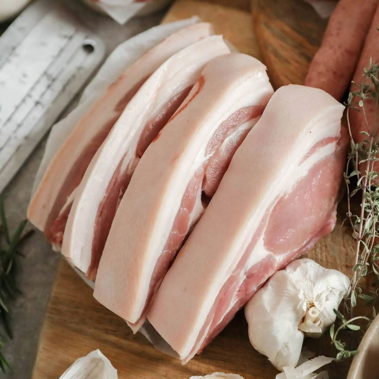 Fresh Primrose Herd pork chops, 500g, showcasing raw, bone-in pork cuts with a pink hue and marbling on a white surface.