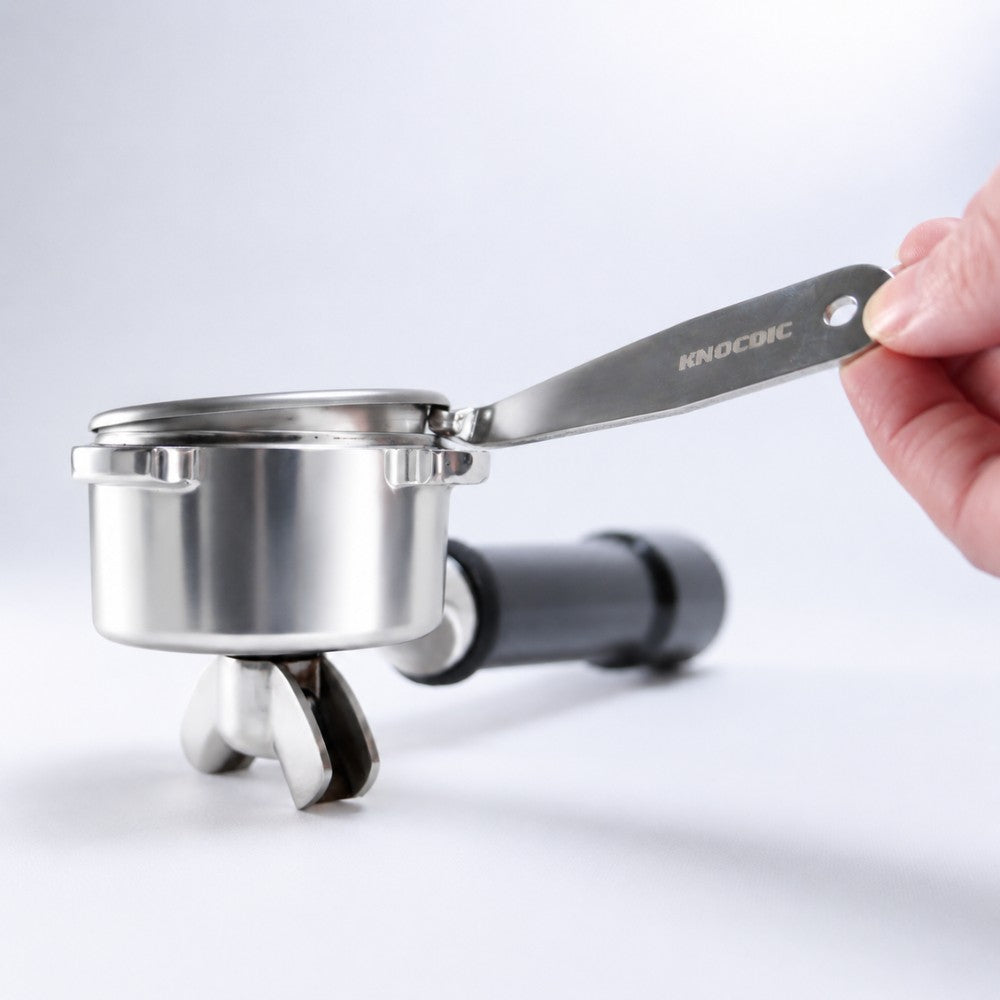 KNOCDIC® portafilter basket lifter tool in use, lifting and removing a coffee portafilter basket for espresso machine maintenance.