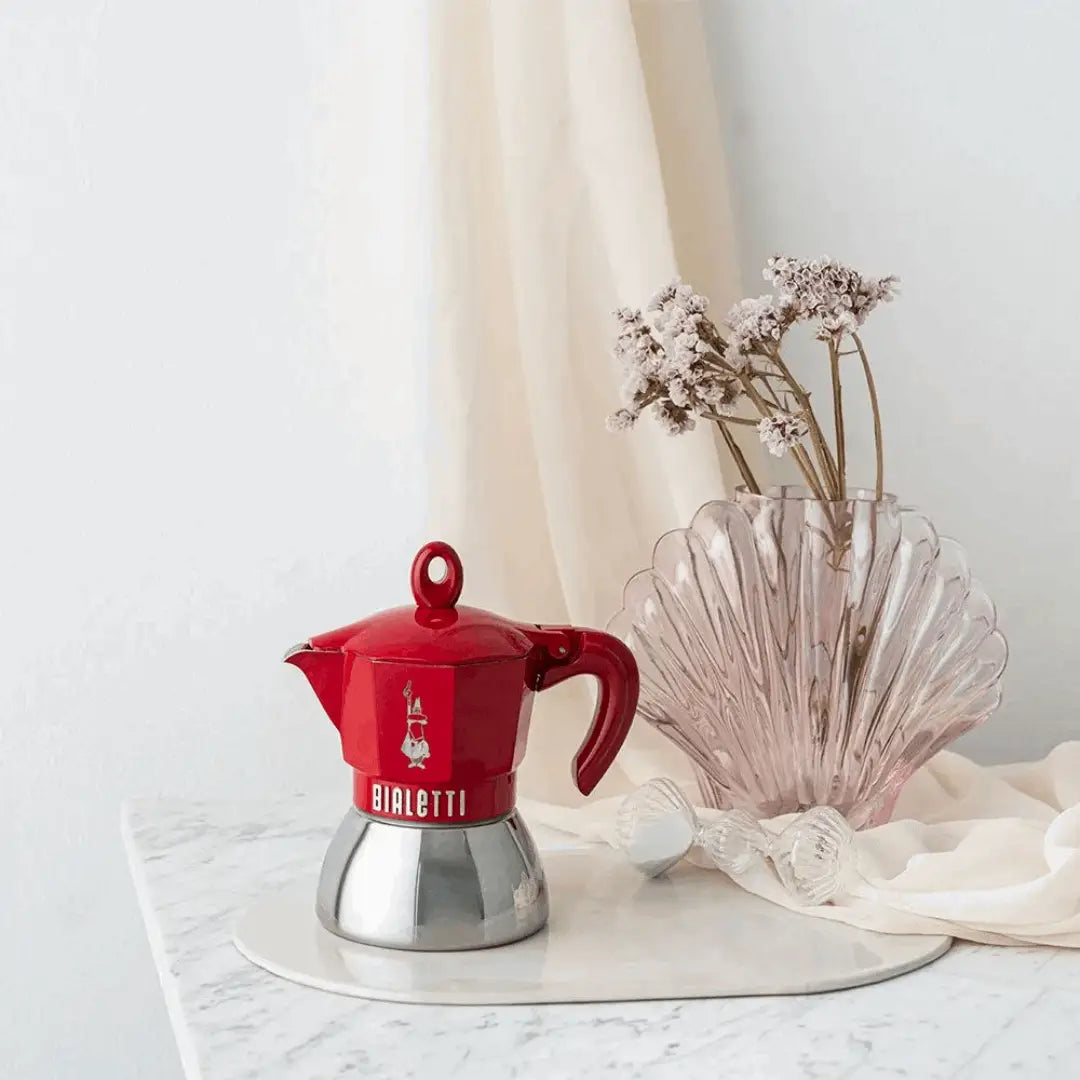 Red Bialetti Moka Induction Exclusive coffee maker by Brew Italia with a sleek metal handle and polished finish.