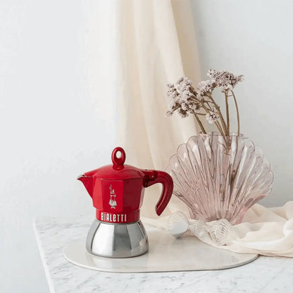 Red Bialetti Moka Induction Exclusive coffee maker by Brew Italia with a sleek metal handle and polished finish.