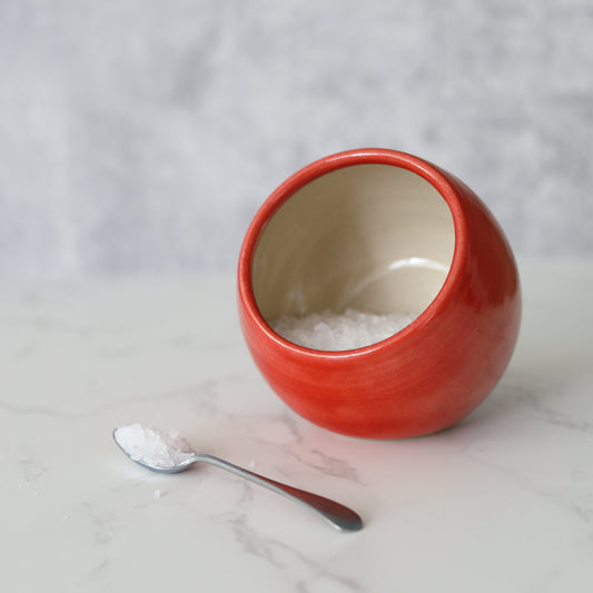 Cherry red salt pig with a small spoon from Katie L Thompson Designs, classic kitchen salt container with a vibrant finish.
