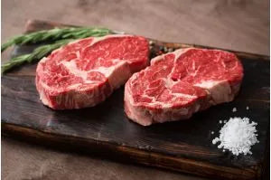 Primrose Herd grass-fed beef ribeye steak on a cutting board, showcasing marbling and fresh quality beef.