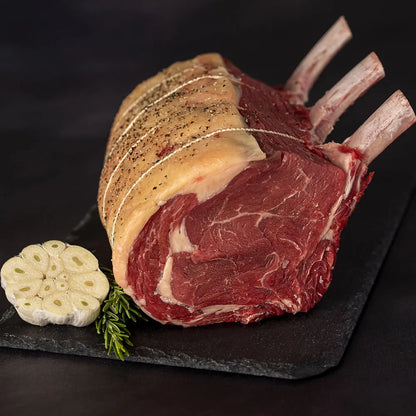 French-trimmed dry-aged bone-in rib of beef joint from Primrose Herd, showcasing marbled beef with exposed bone and rich texture.