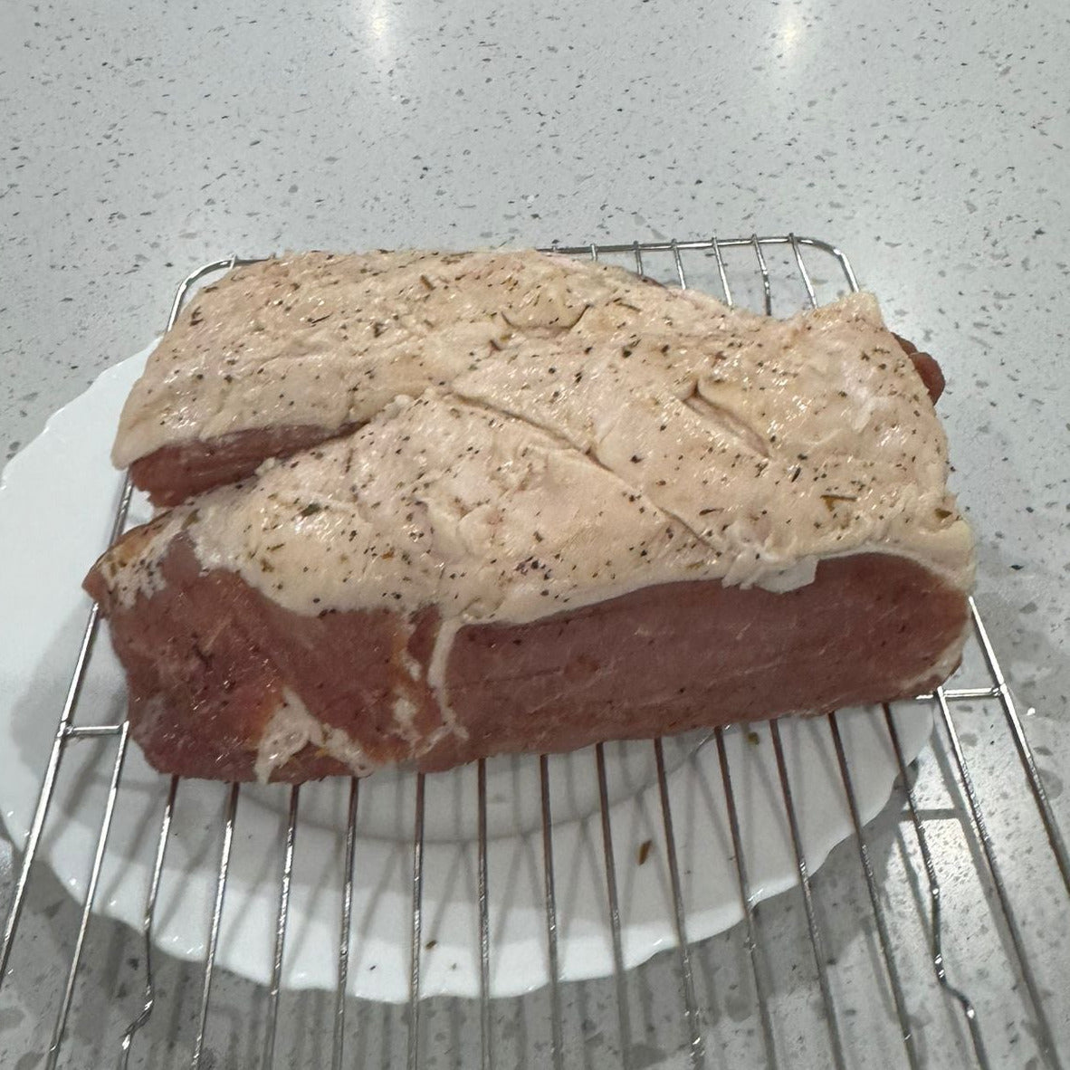 FireFly Barbecue Bacon Curing Kit with rosemary and black pepper, showing cured bacon strips infused with herbs and spices.