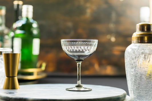 Set of four smoky crystal champagne saucers with oval design by The Vintage List, featuring elegant, curved glassware for celebratory drinks.