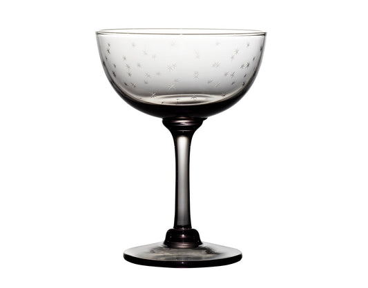 Four smoky crystal champagne saucers with star designs, elegant glassware from The Vintage List, on a reflective surface.