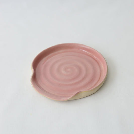 Blush pink ceramic spoon rest with a classic design by Katie L Thompson Designs, ideal for holding cooking utensils.