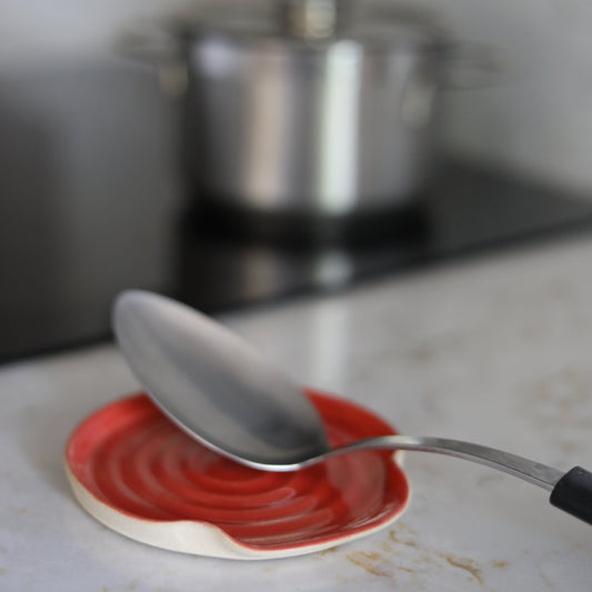 Cherry red ceramic spoon rest from Katie L Thompson Designs, featuring a classic round shape for kitchen use.