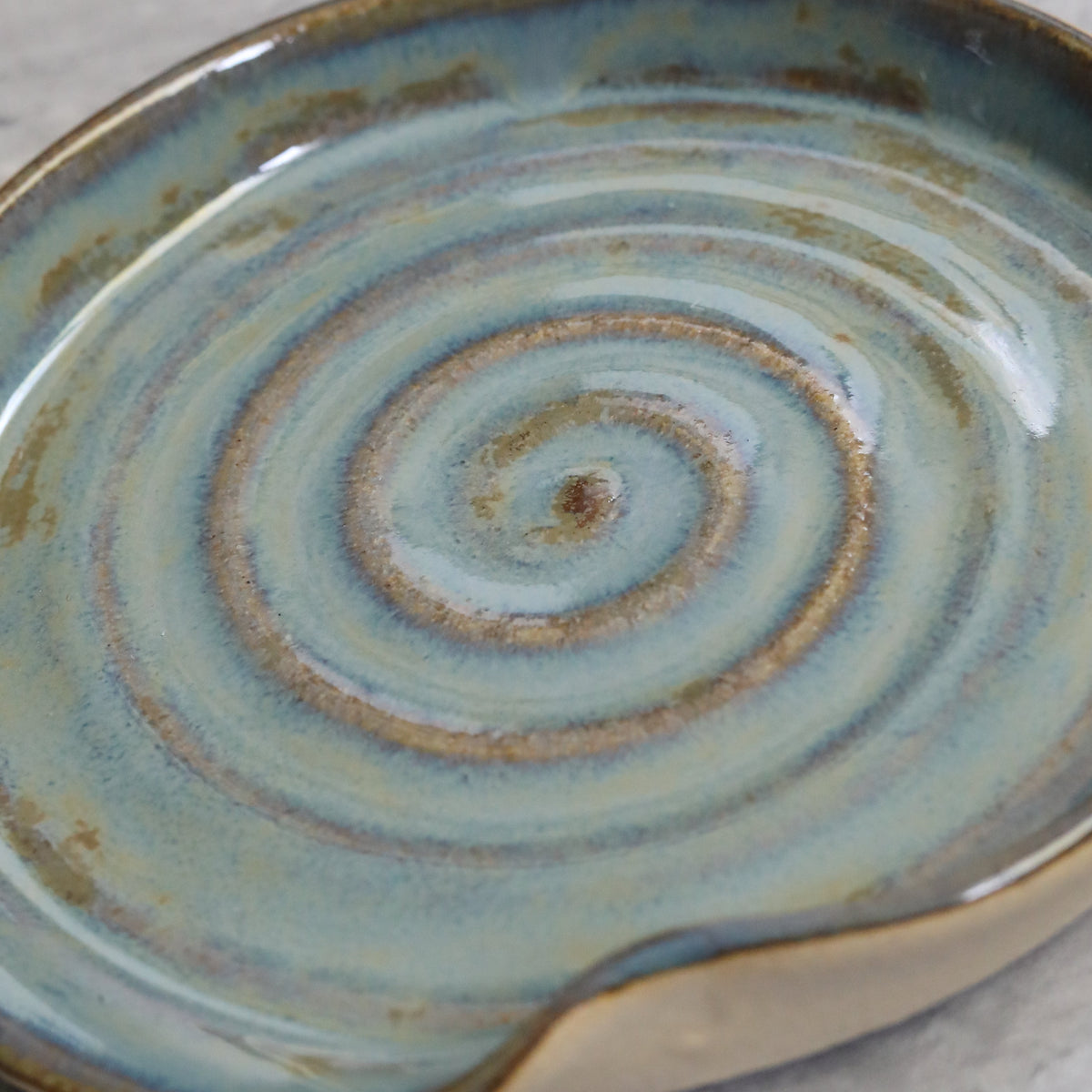 Seafoam blue ceramic spoon rest with a spiral design by Katie L Thompson Designs, ideal for kitchen countertop use.