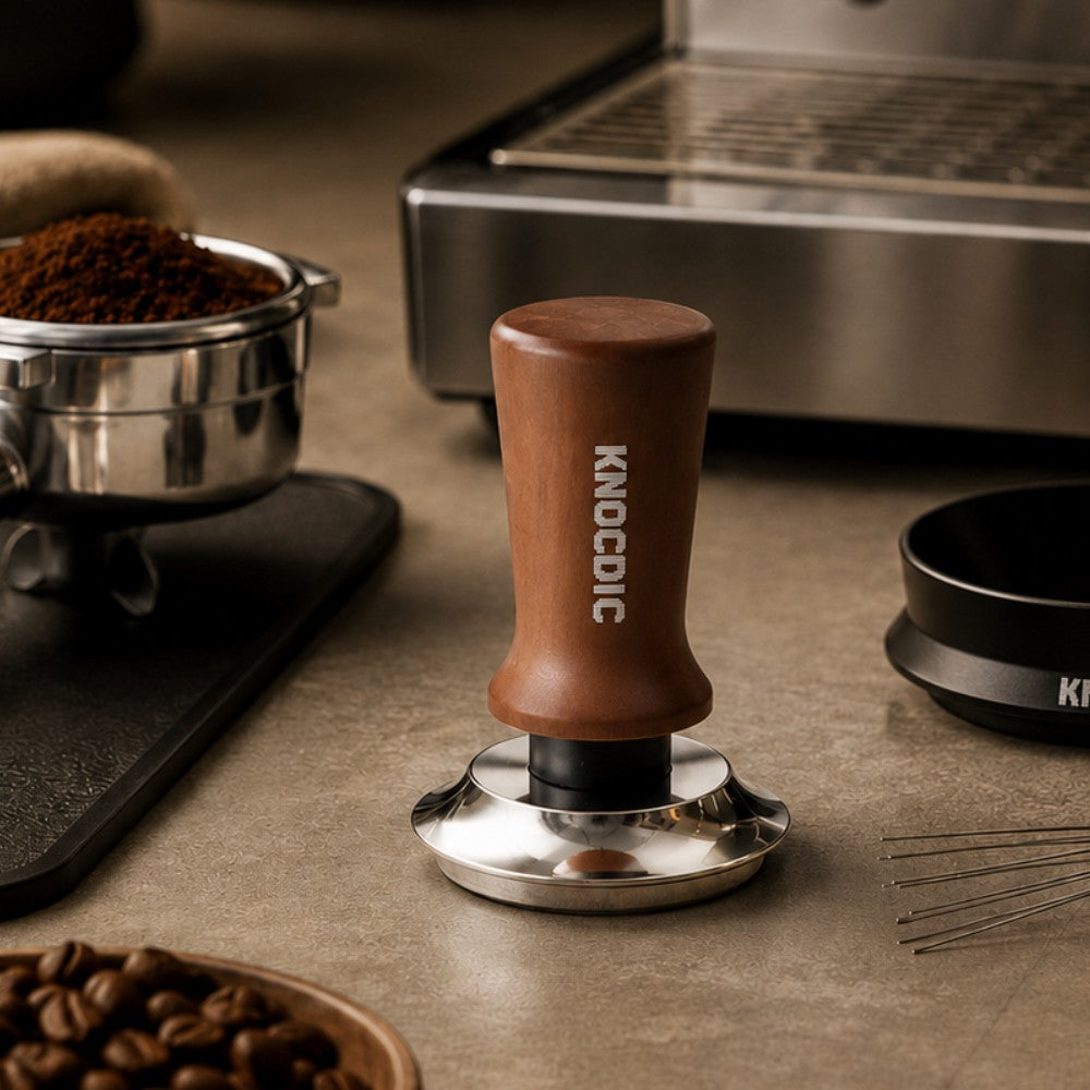 KNOCDIC® espresso tamper with spring-loaded base, showing the tamper in a lifestyle setting for professional coffee brewing.