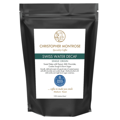 Christopher Montrose Coffee Swiss Water Decaf Arabica coffee beans in a transparent bag, showing the light brown roasted beans inside.