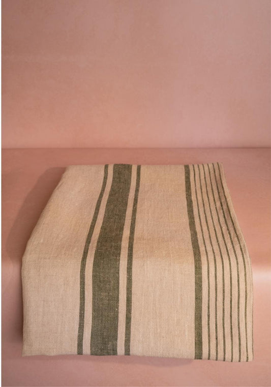 Green striped Jemima linen tablecloth by Casa by Josephine Jenno, draped over a table showing its soft fabric and stylish pattern.