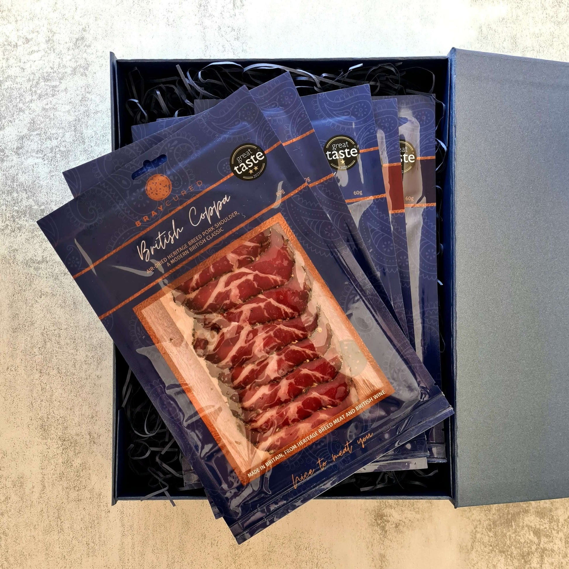 Assorted Bray Cured charcuterie selection with five packs of cured meats in a box, showcasing a variety of slices and textures.