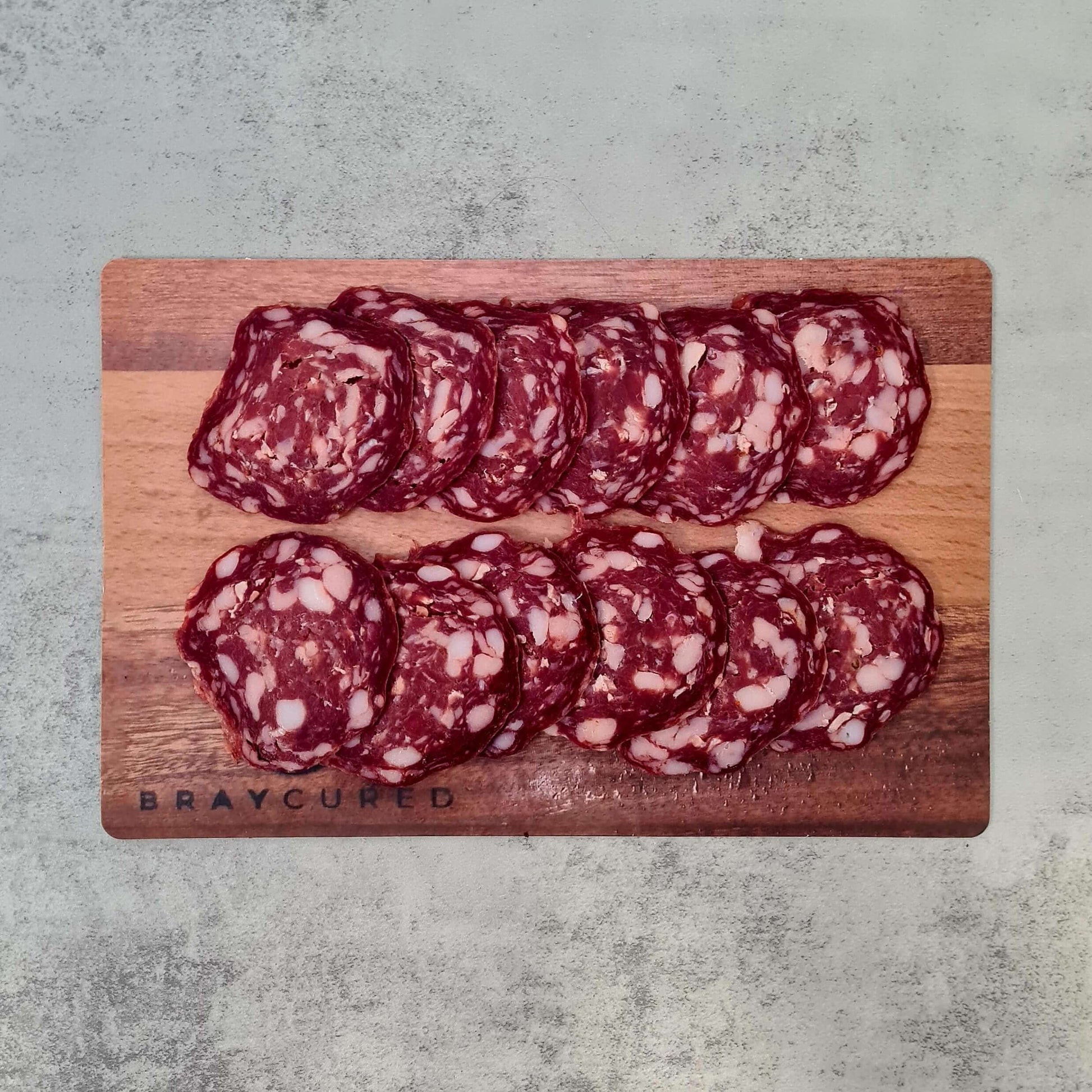 Sliced venison Old Fashioned Salami by Bray Cured on a wooden charcuterie board, showcasing its rustic appearance and rich texture.